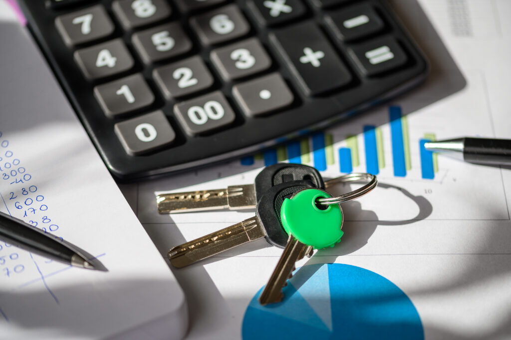 Close-up of keys on a desk with a calculator and financial documents.